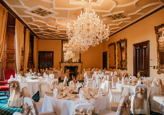 Dining set up with white and gold accents and chandeliers hanging above